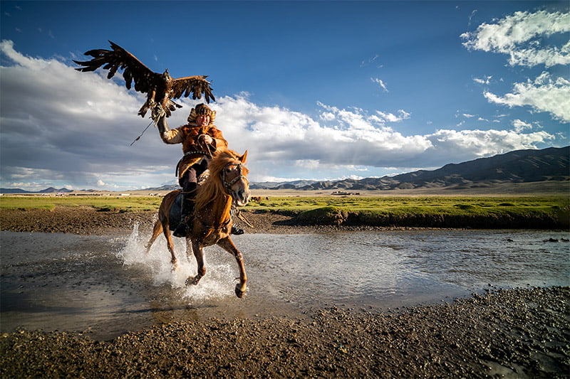 Botei Rys, a Kazakh Eagle Hunter crossing a river with his eagle from Altantsögts district of Bayan-Ölgii Province in western Mongolia.