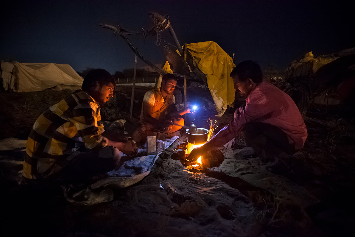 Three camel shepherds are preparing their food at night 